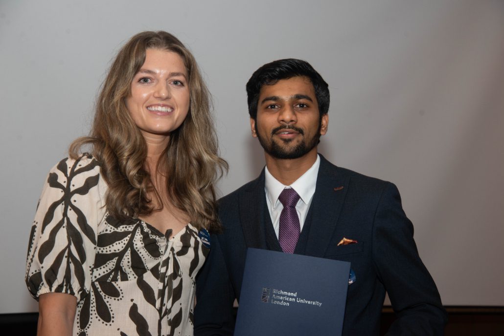 Two people are posing with a certificate from ϲֱֳ, The American University in London. One person is wearing a patterned blouse; the other, a suit.